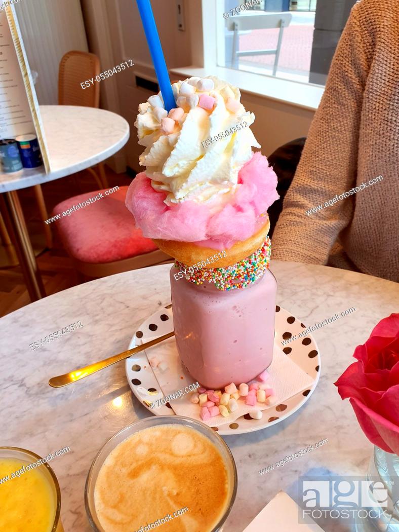 Stock Photo: Pink strawberry freakshake with sweets, donuts and wipped cream in cafe, extreme milkshake sugar.