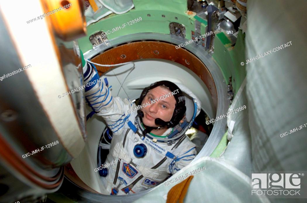 Stock Photo: Cosmonaut Yury I. Onufrienko, Expedition Four mission commander, wearing a Russian Sokol suit, moves through a hatch in the Soyuz 3 spacecraft that is docked to.