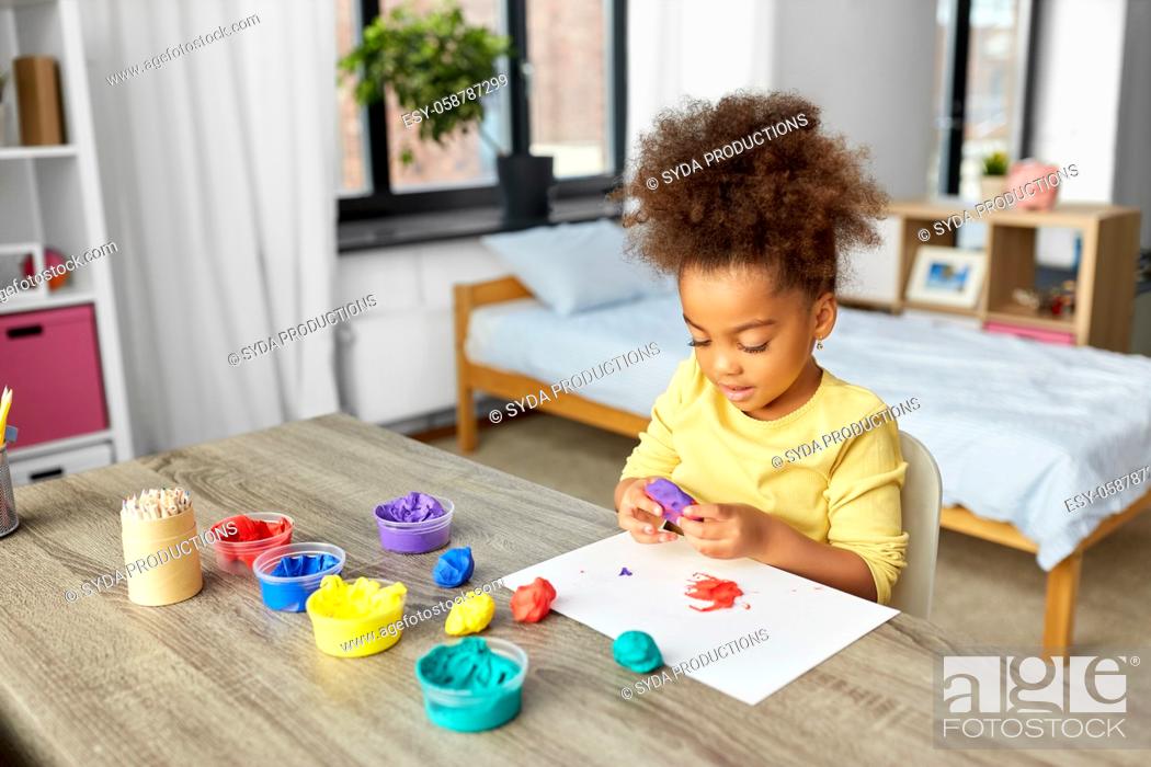 Stock Photo: little girl with modeling clay playing at home.