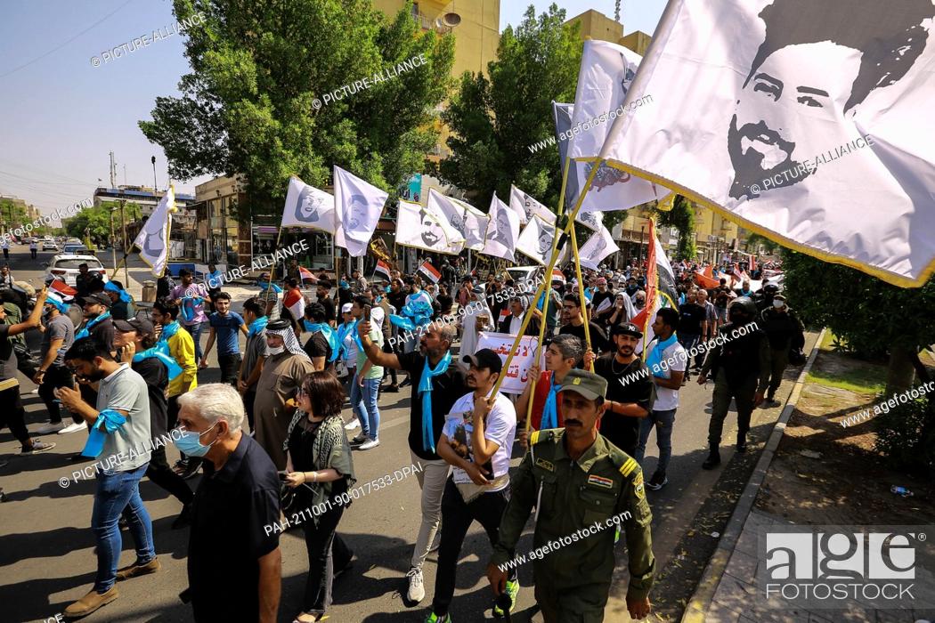 Stock Photo: 01 October 2021, Iraq, Baghdad: Iraqi demonstrators wave flags bearing pictures of those who killed in October 2019 anti-government protests.