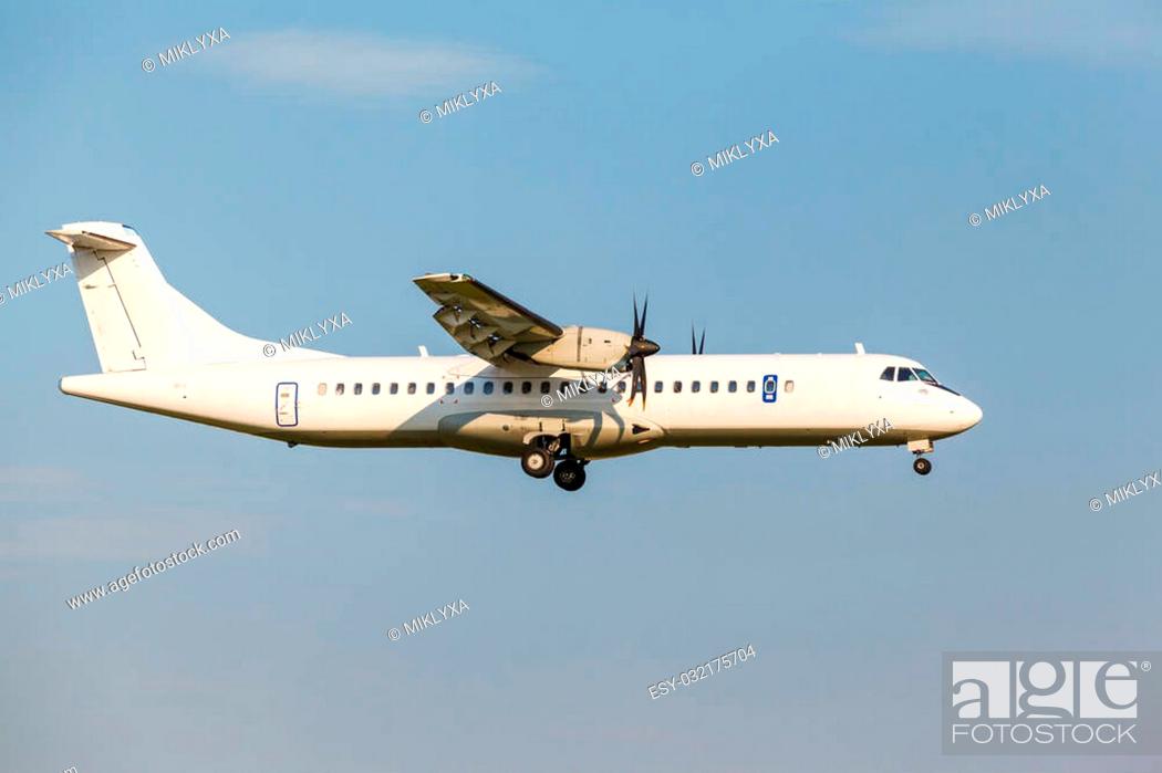 Stock Photo: white passenger turboprop aircraft with the gear landing on blue sky background.