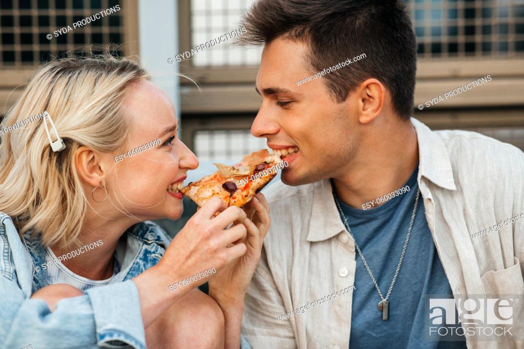 Photo de stock: happy couple eating pizza outdoors.