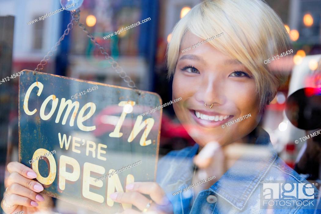 Stock Photo: Portrait confident young female shop owner holding Open sign at window.