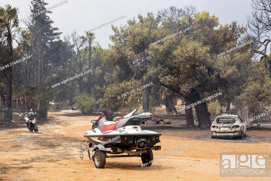 Stock Photo: 24 July 2018, Greece, Mati: A jet ski, motorcycle and car stand on the road after a fire raged there last night. According to new information.
