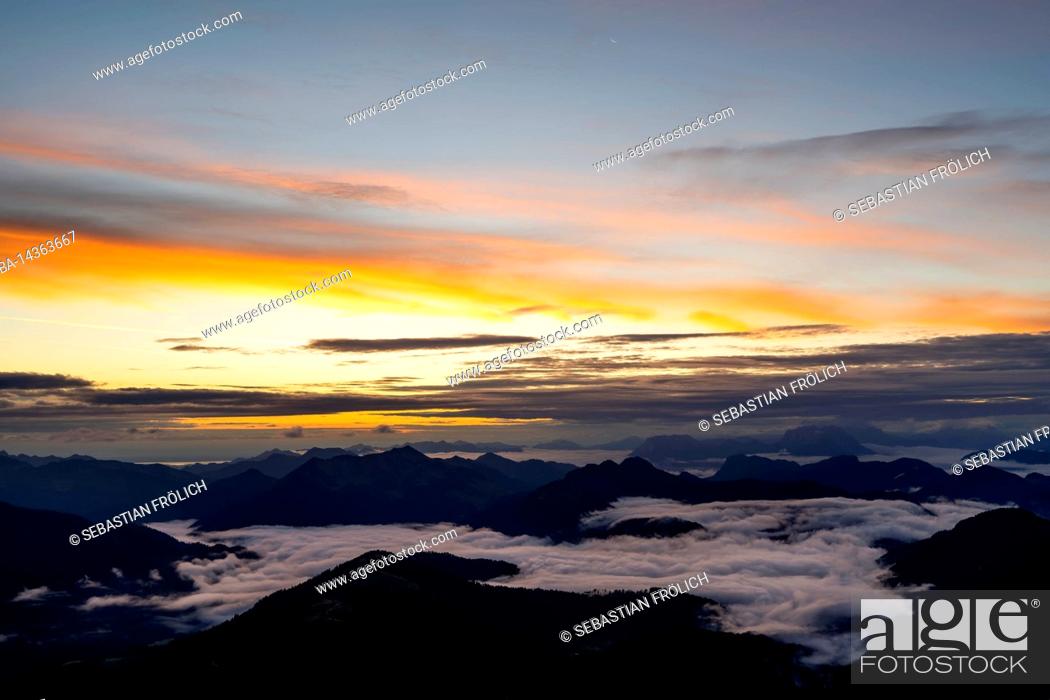 Stock Photo: Sunrise with sun star and light colored clouds, while in the valley fog and clouds are moving. View from Guffert (2194m) in Rofan early in the morning.
