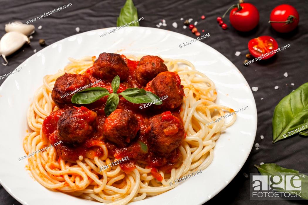 Stock Photo: Spaghetti pasta with meatballs and tomato sauce on black background.