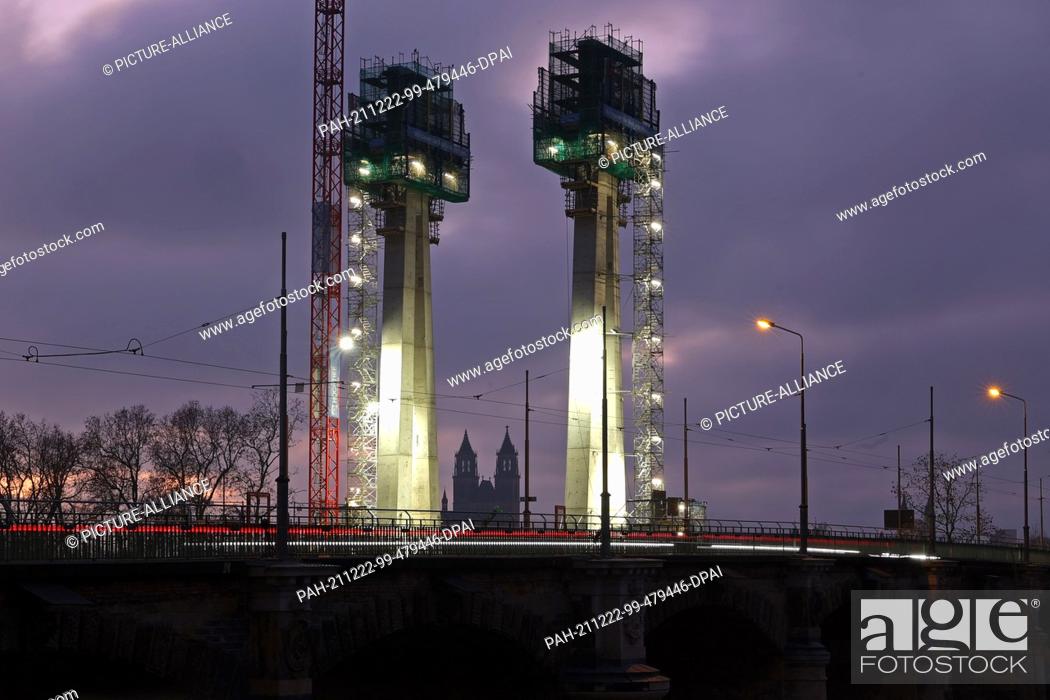 Stock Photo: 22 December 2021, Saxony-Anhalt, Magdeburg: View of the construction site with the two pylons at dusk. The new construction of the Strombrücke was started in.