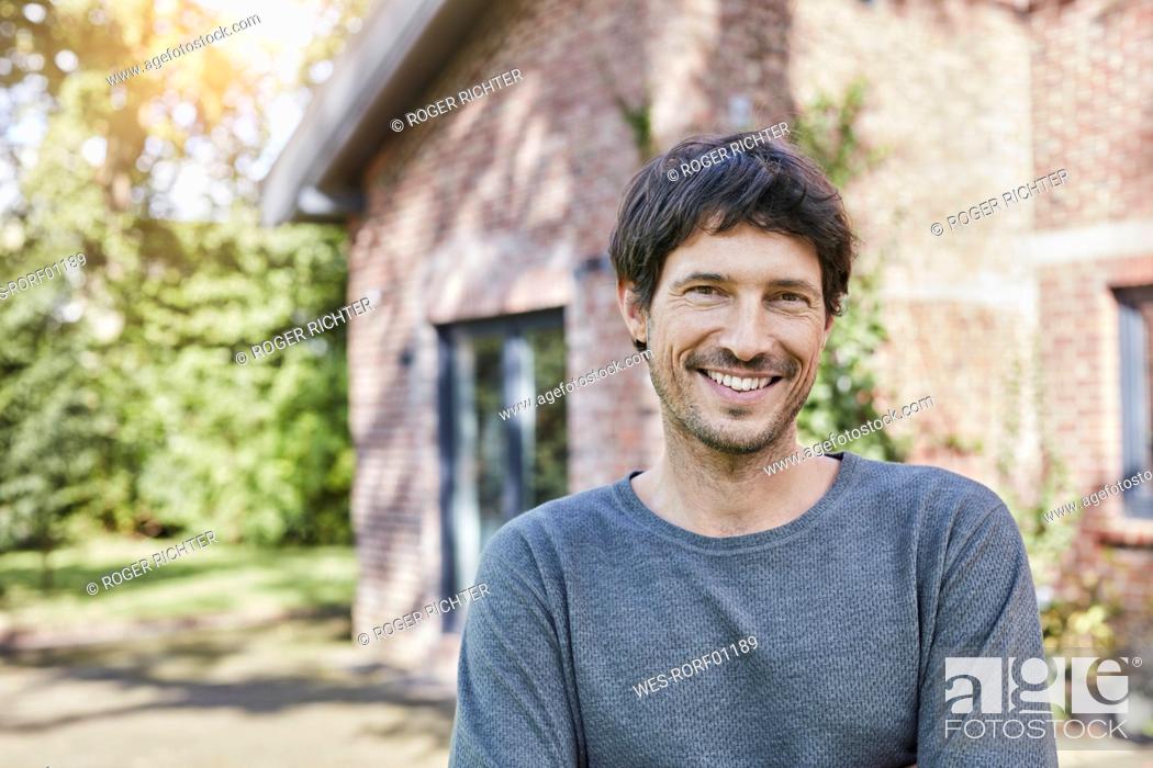 Stock Photo: Portrait of smiling man in front of his home.