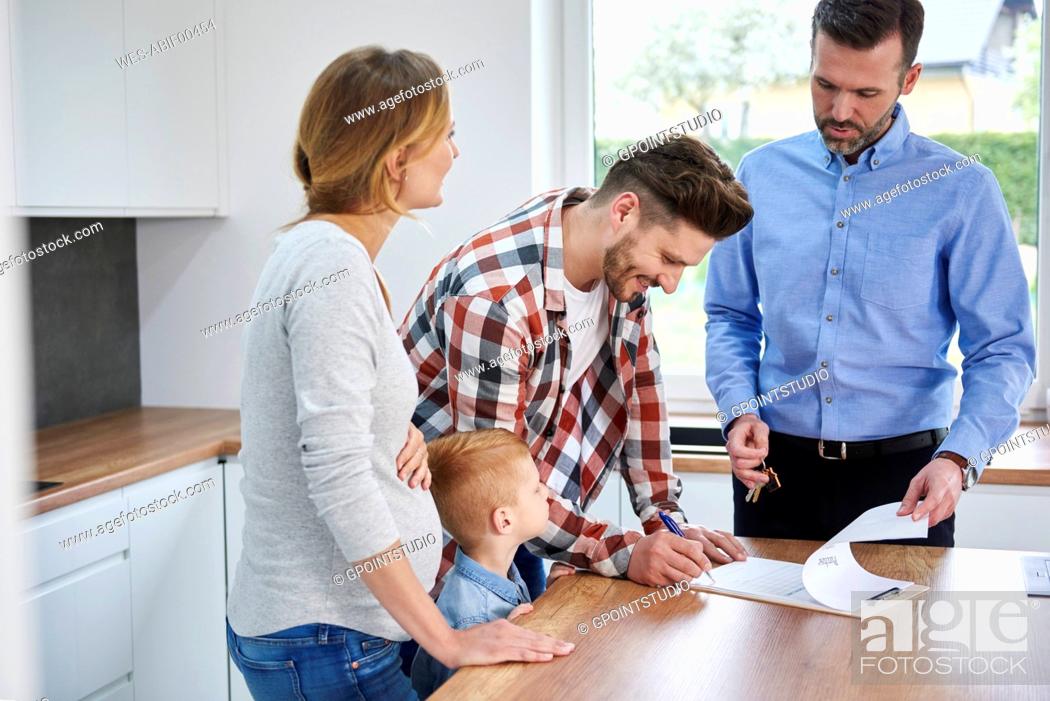 Stock Photo: Family with real estate agent signing contract in kitchen of new apartment.