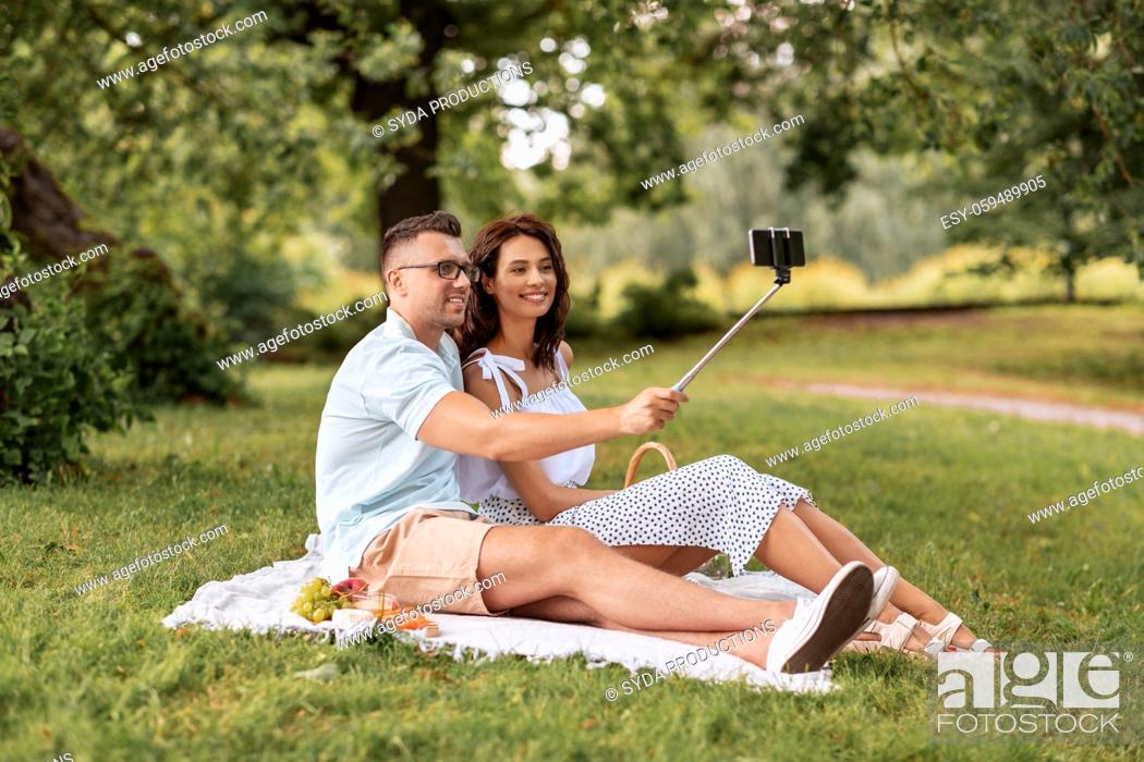 Stock Photo: happy couple taking selfie at picnic in park.