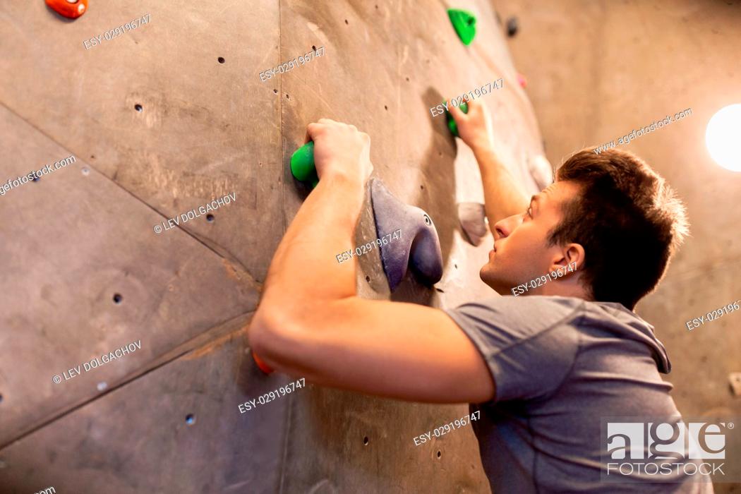 Stock Photo: fitness, extreme sport, bouldering, people and healthy lifestyle concept - young man exercising at indoor climbing gym.