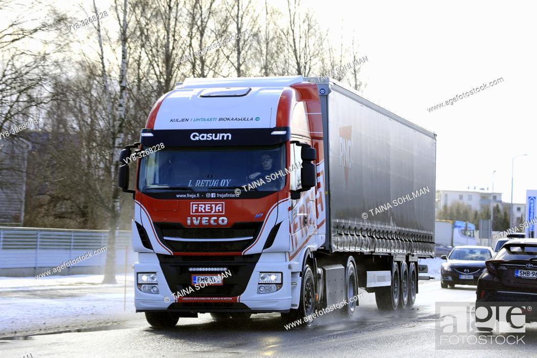 Stock Photo: Salo, Finland - March 9, 2019: Biogas fueled Iveco Stralis NP truck L. Retva Oy pulls trailer on wet road among traffic on a day of early spring.