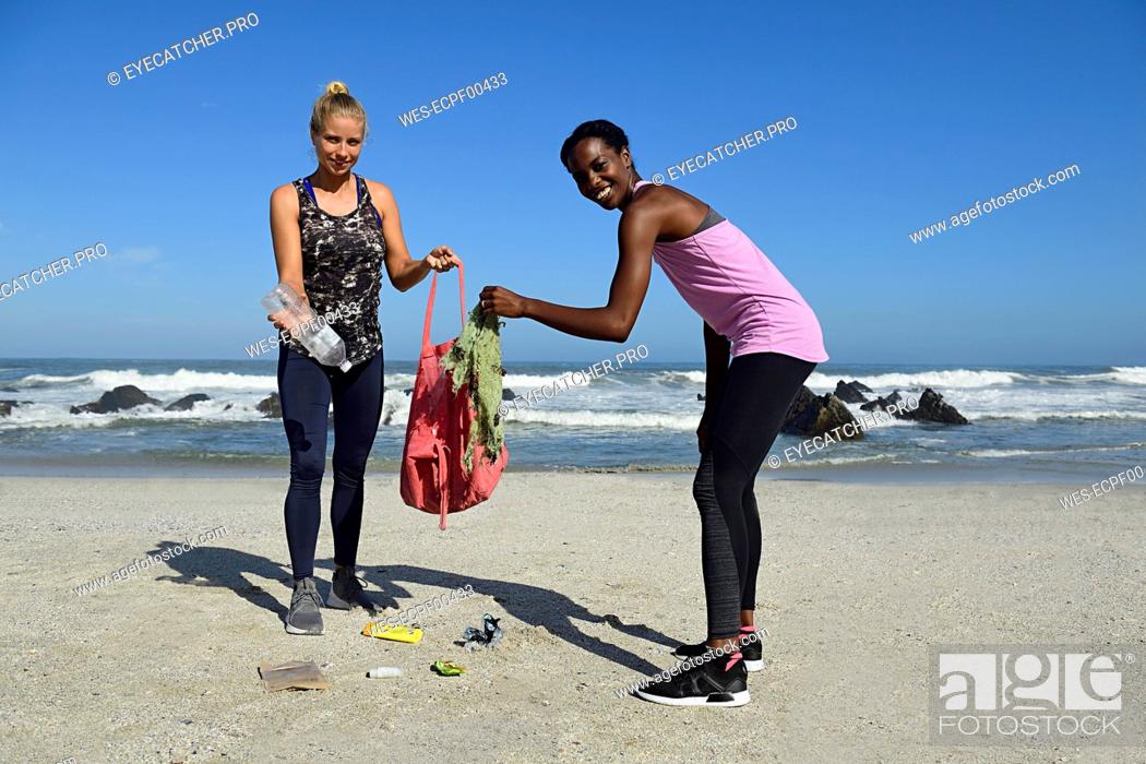 Stock Photo: Portrait of two smiling women cleaning the beach from plastic waste.