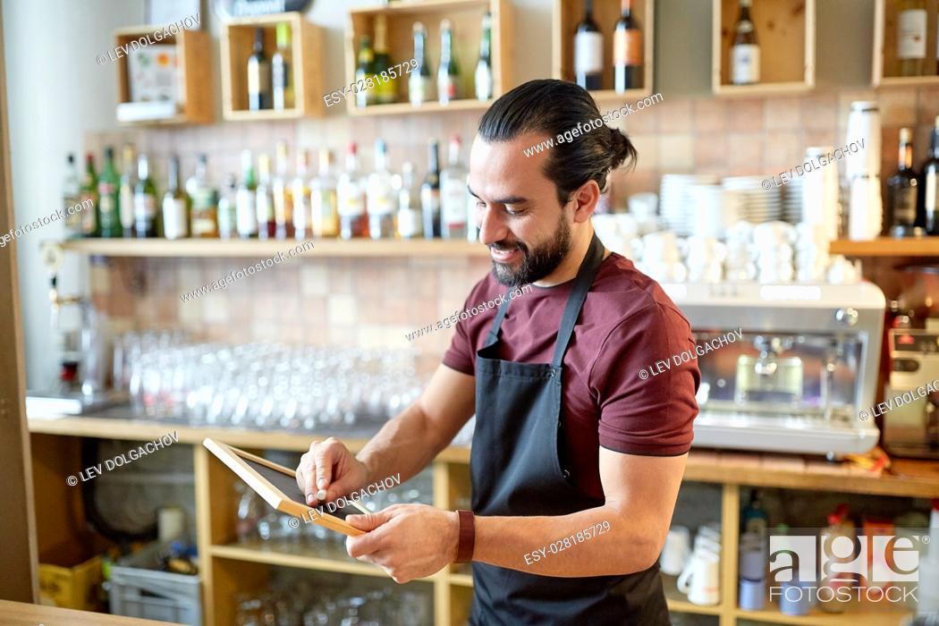 Stock Photo: small business, people and service concept - happy man or waiter in apron with black chalkboard banner at bar or coffee shop.