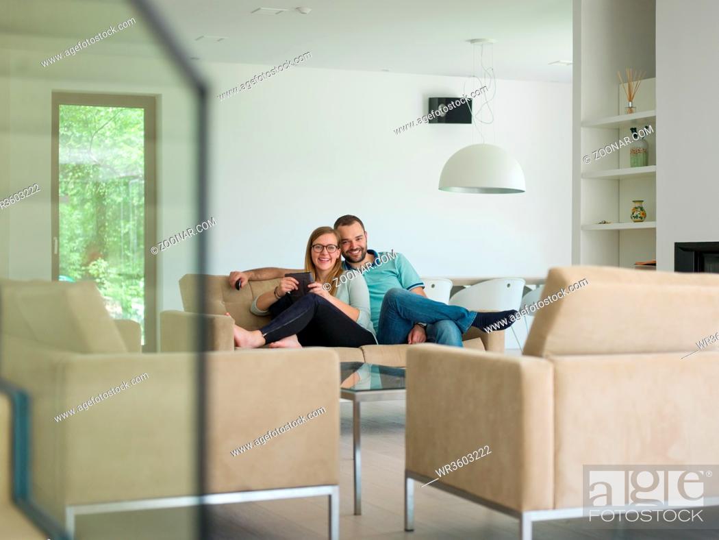 Imagen: Young couple relaxes on the sofa in the luxury living room, using a tablet and remote control.