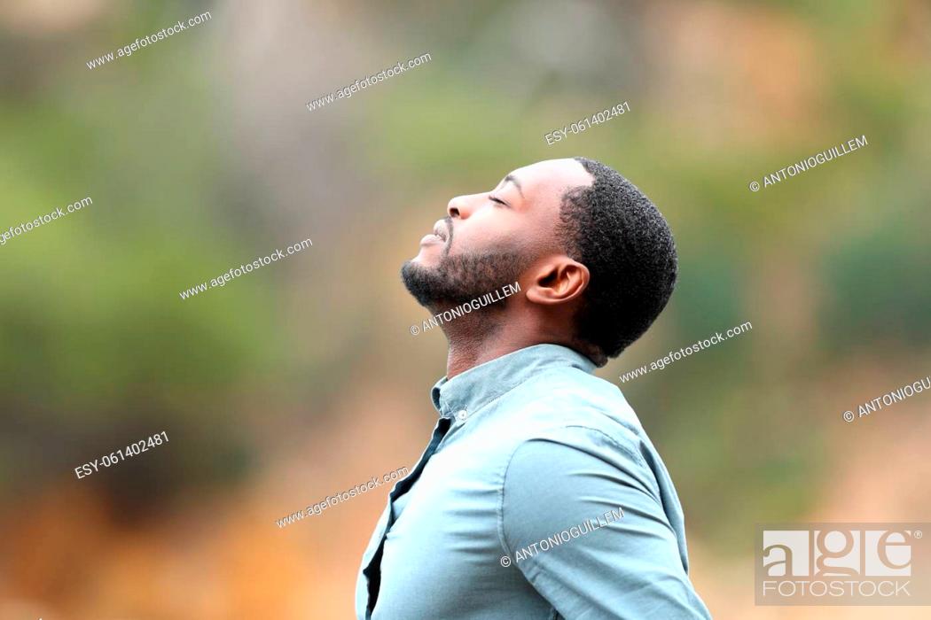 Stock Photo: Side view portrait of a man with black skin breaths fresh air outside.
