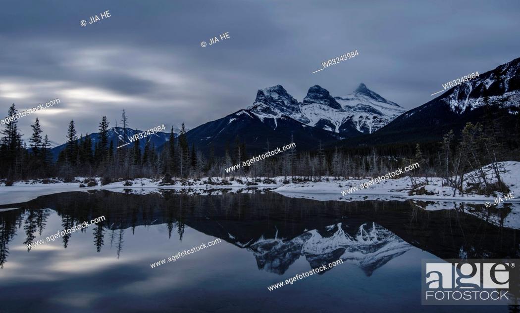 Stock Photo: Canadian Rockies on a gloomy day, showing The Three Sisters over lake reflection, Alberta, Canada, North America.