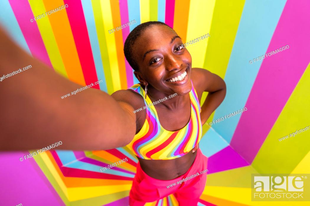 Stock Photo: Beautiful african american young woman dancer having fun inside a rainbow box room - Cool and stylish afro adult woman portrait on multicolored background.