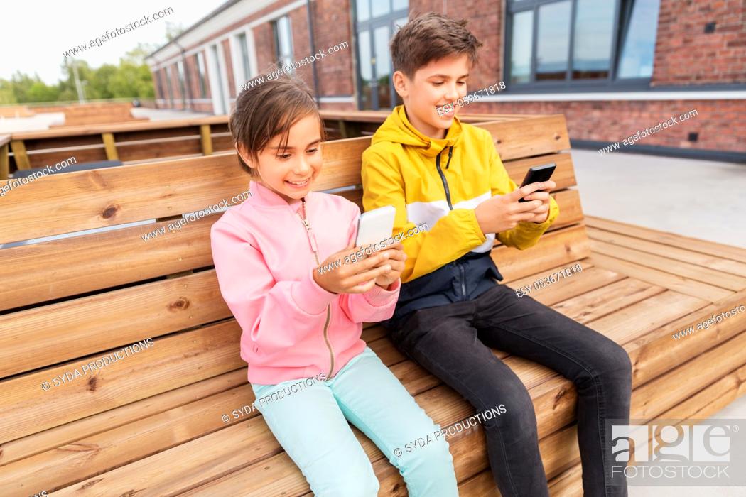 Stock Photo: children with smartphones sitting on street bench.