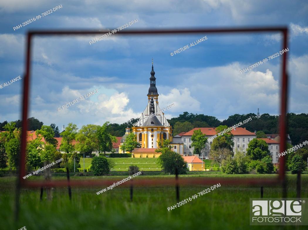 Stock Photo: 12 May 2020, Brandenburg, Neuzelle: View through an empty frame to the catholic church of the monastery Neuzelle. In the Neuzelle monastery garden in the.
