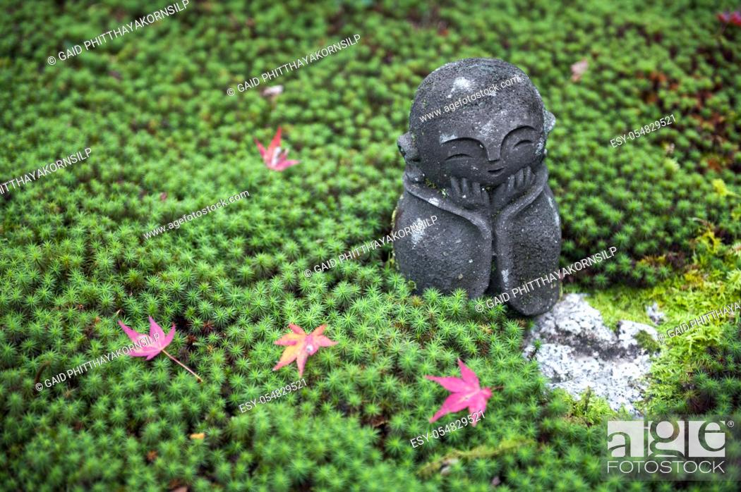 Stock Photo: Stone statue of Jizo on ground covered by green star moss and red maple leaves during autumn in a garden at Enkoji temple in Kyoto, Japan.