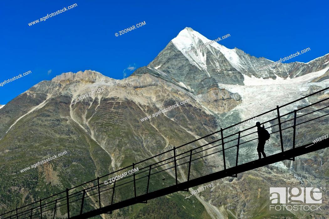 Stock Photo: Wanderer vor dem Weisshorn Gipfel im Gegenlicht auf der Charles Kuonen Hängebrücke, längste Fussgänger-Hängebrücke der Welt, Randa, Wallis.