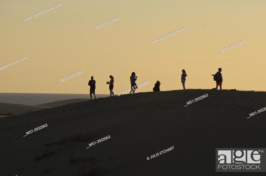 Photo de stock: People watching the sunset at and taking selfie photos at Maspalomas sand dunes, near Playa de los Ingleses, Gran Canaria, Spain.