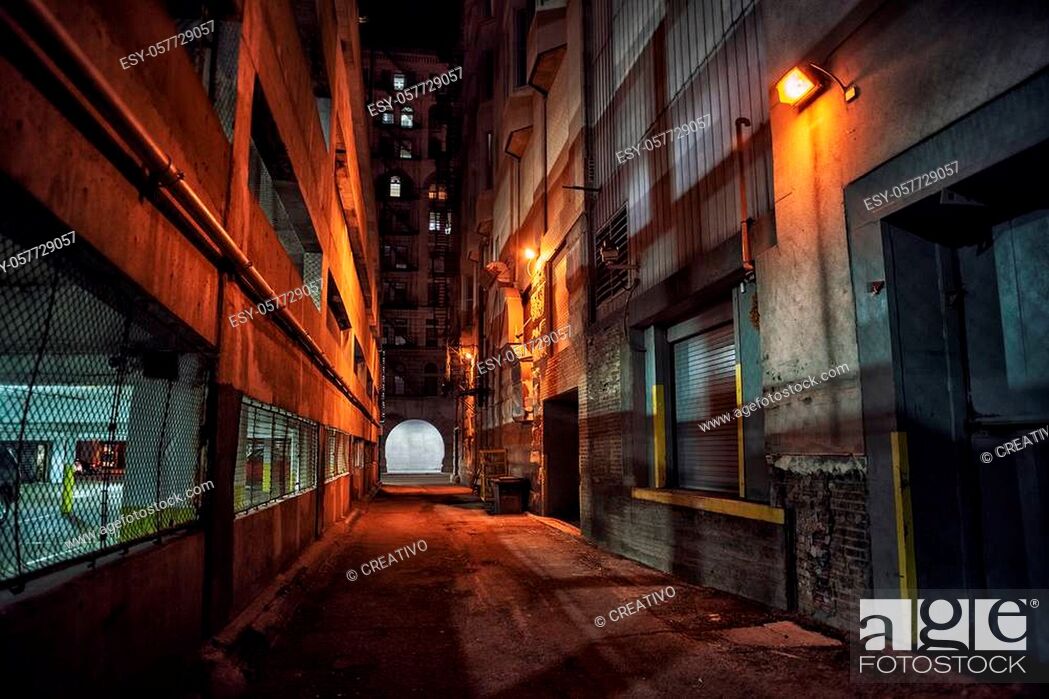 Stock Photo: Dark and eerie downtown urban city alley with a loading dock next to a parking garage at night.