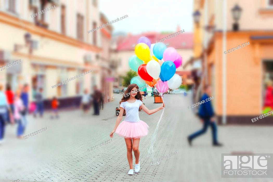 Stock Photo: Teenage birthday. Pretty girl with big colorful balloons in the street of an old town.