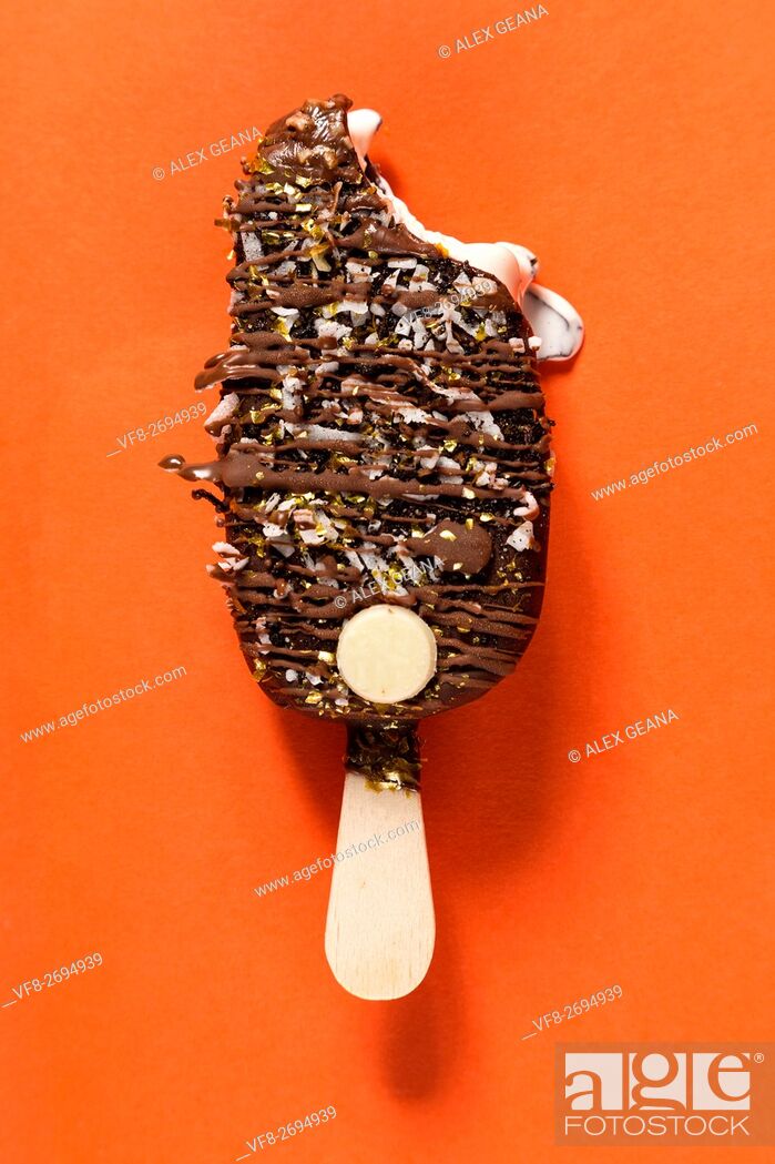 Stock Photo: A chocolate bar isolotated on an orange background, drizled with toppings and more chocolate.