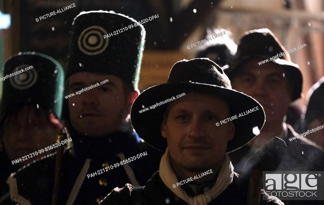 Stock Photo: 10 December 2022, Saxony, Oberwiesenthal: Actors of miners' clubs stand in the snowfall on the market square. A traditional mining parade took place there.