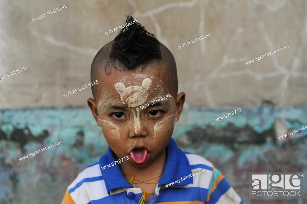 Stock Photo: Yangon, Myanmar, Asia - Portrait of a little boy who sticks out his tongue and who has applied Thanaka paste onto his face.