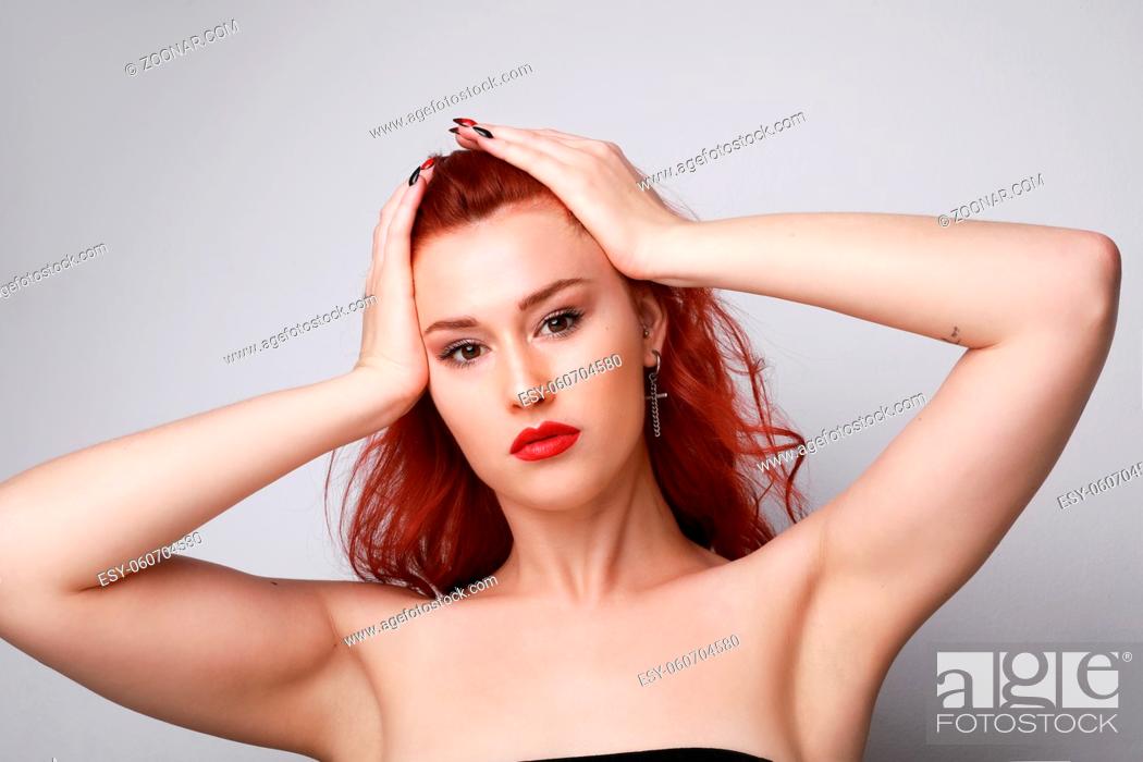 Stock Photo: Close-up of young woman with red hair posing over grey background. High quality photo.
