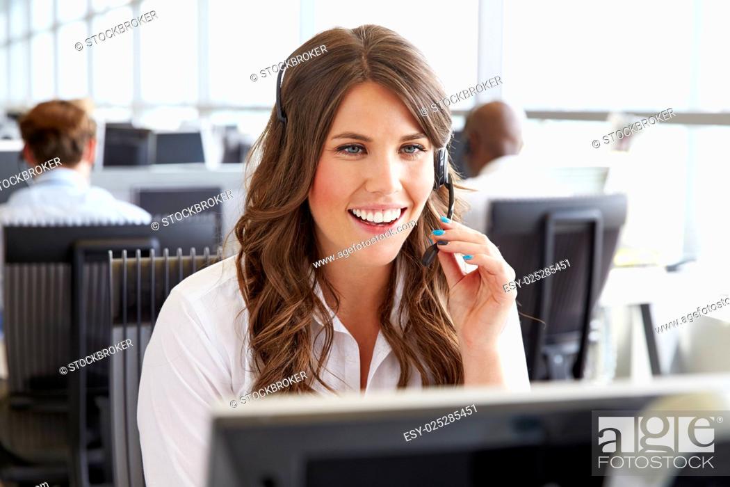 Stock Photo: Young woman working in a call centre, holding headset.