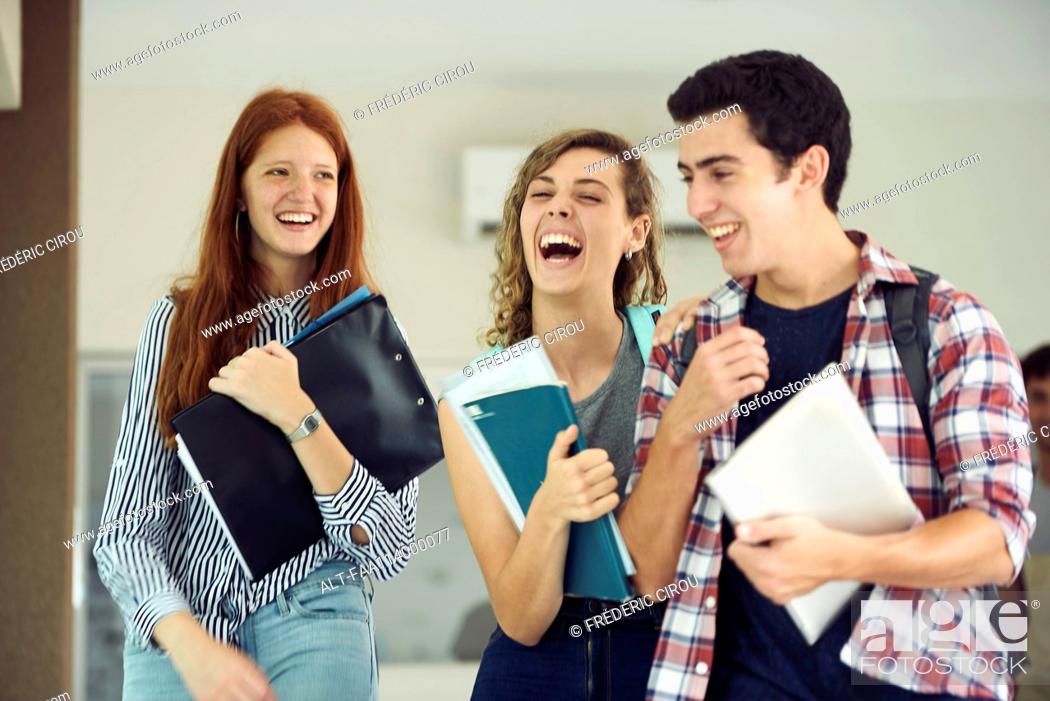 Stock Photo: Classmates laughing together while walking in school corridor.