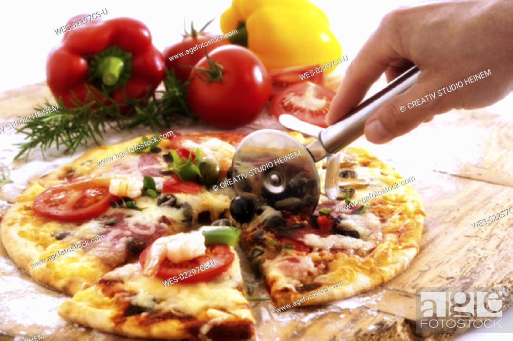 Stock Photo: Person cutting a slice of pizza.