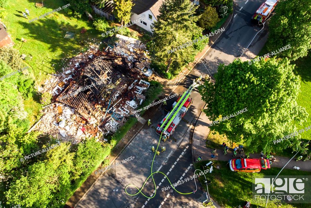 Stock Photo: 23 May 2019, Schleswig-Holstein, Wohltorf: Firefighters are standing in front of the ruins of a house that was destroyed in a fire.