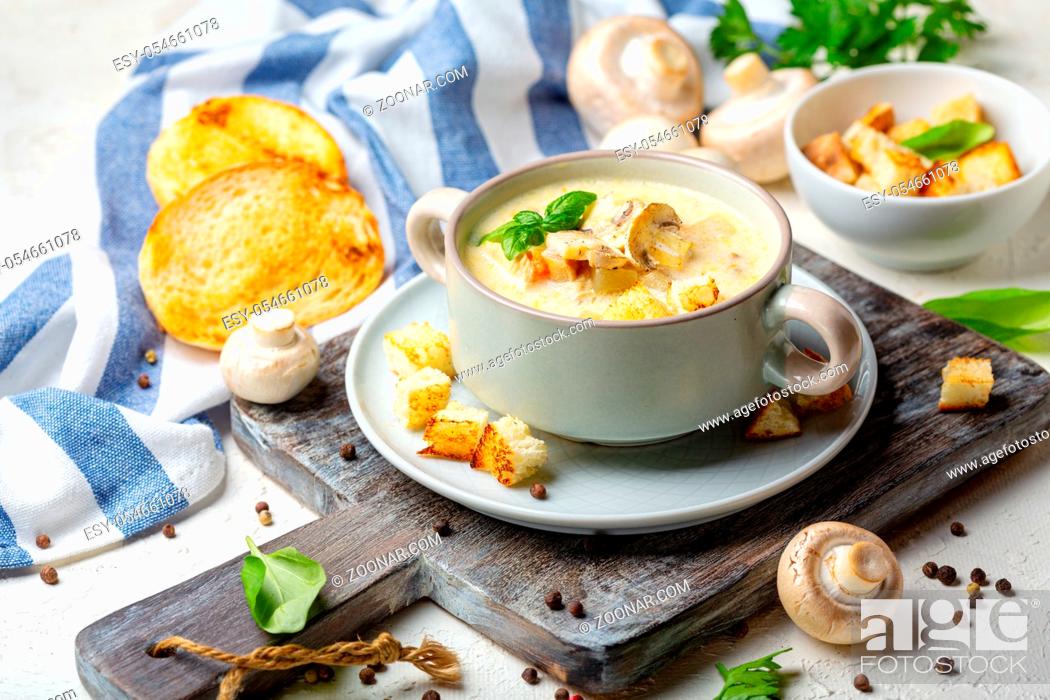 Stock Photo: Bowl of chicken cream soup with mushrooms, croutons and green basil on a wooden serving board, selective focus.