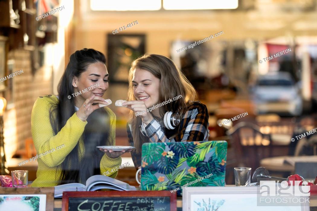 Stock Photo: Young female college students studying, eating dessert at cafe window.