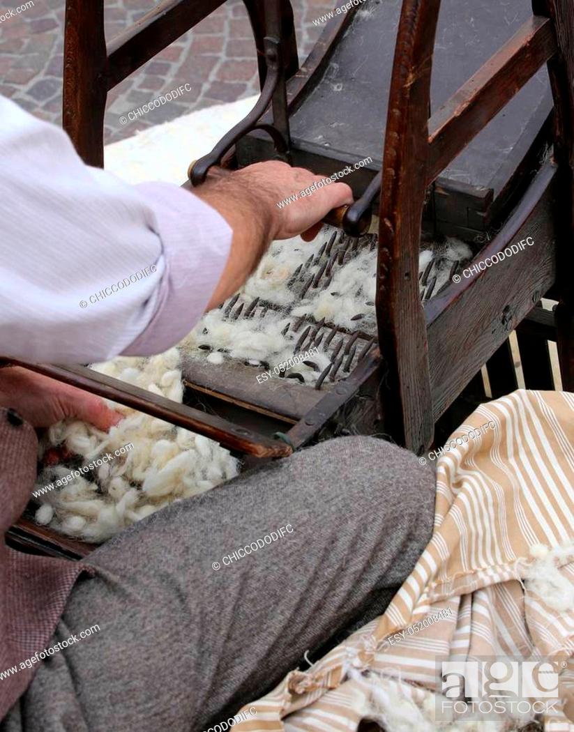 Stock Photo: Elder carder while carding wool or cotton with old wooden machine to make the cushions and mattresses.