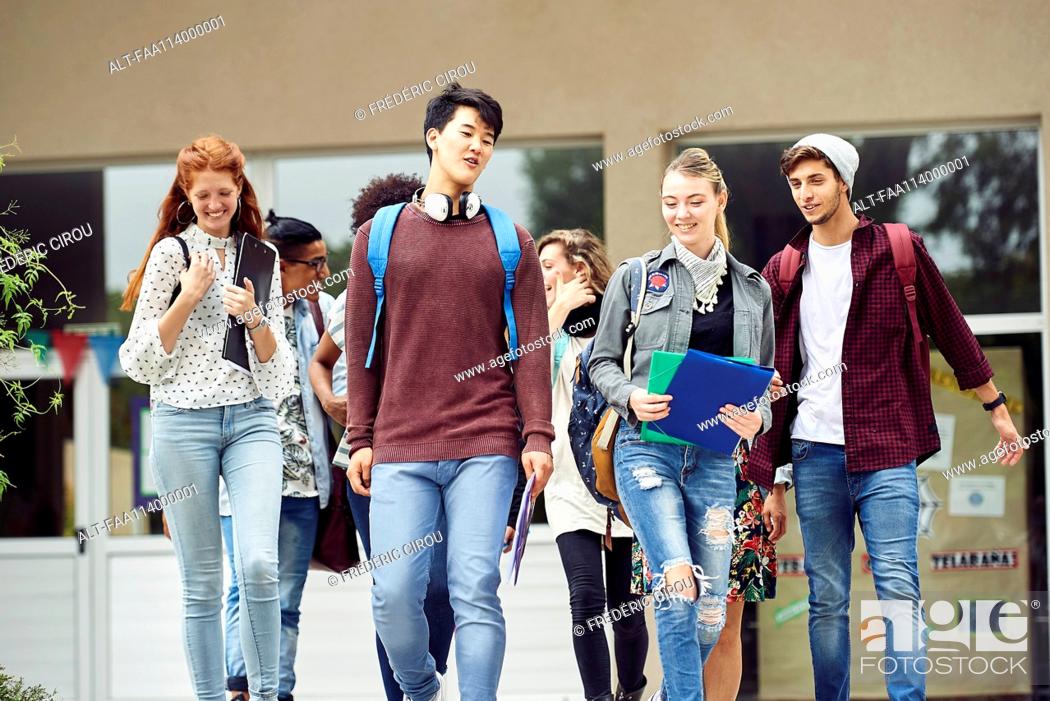 Stock Photo: College students chatting while walking on campus between classes.