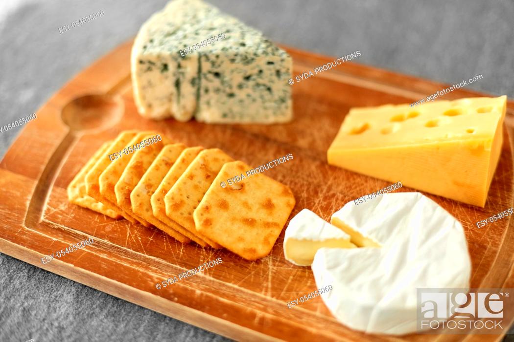 Stock Photo: different cheeses and crackers on wooden board.