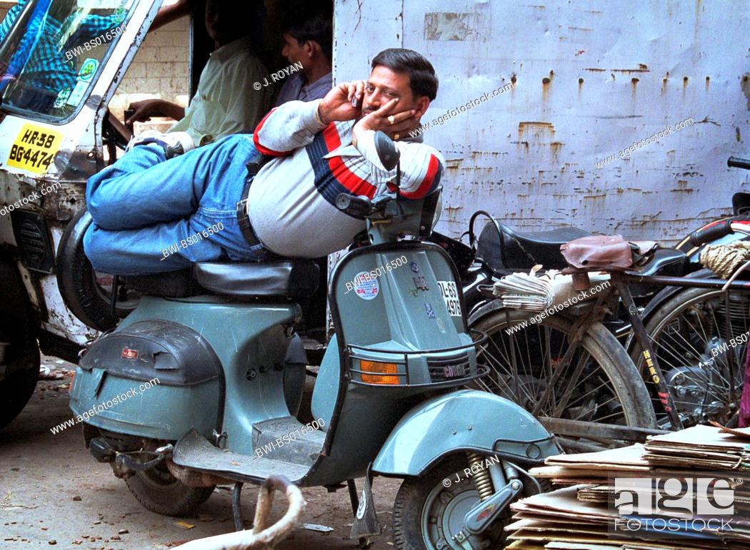 Brace At vise Revolutionerende Indian man lying on scooter and using mobile phone, India, Delhi,  New-Delhi, Stock Photo, Picture And Rights Managed Image. Pic. BWI-BS016500  | agefotostock