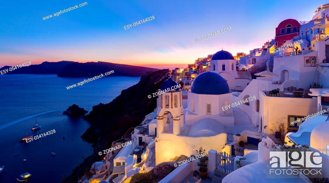 Stock Photo: Cityscape of Oia, traditional greek village with blue domes of churches, Santorini island, Greece at dusk.
