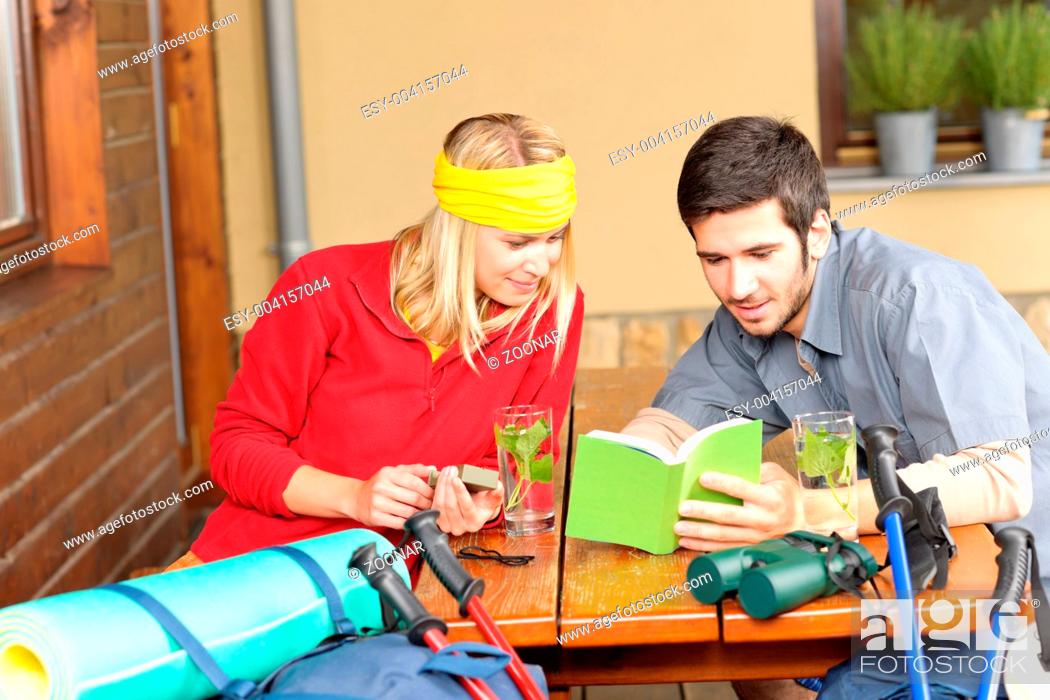 Stock Photo: Tramping young couple relax looking in book.