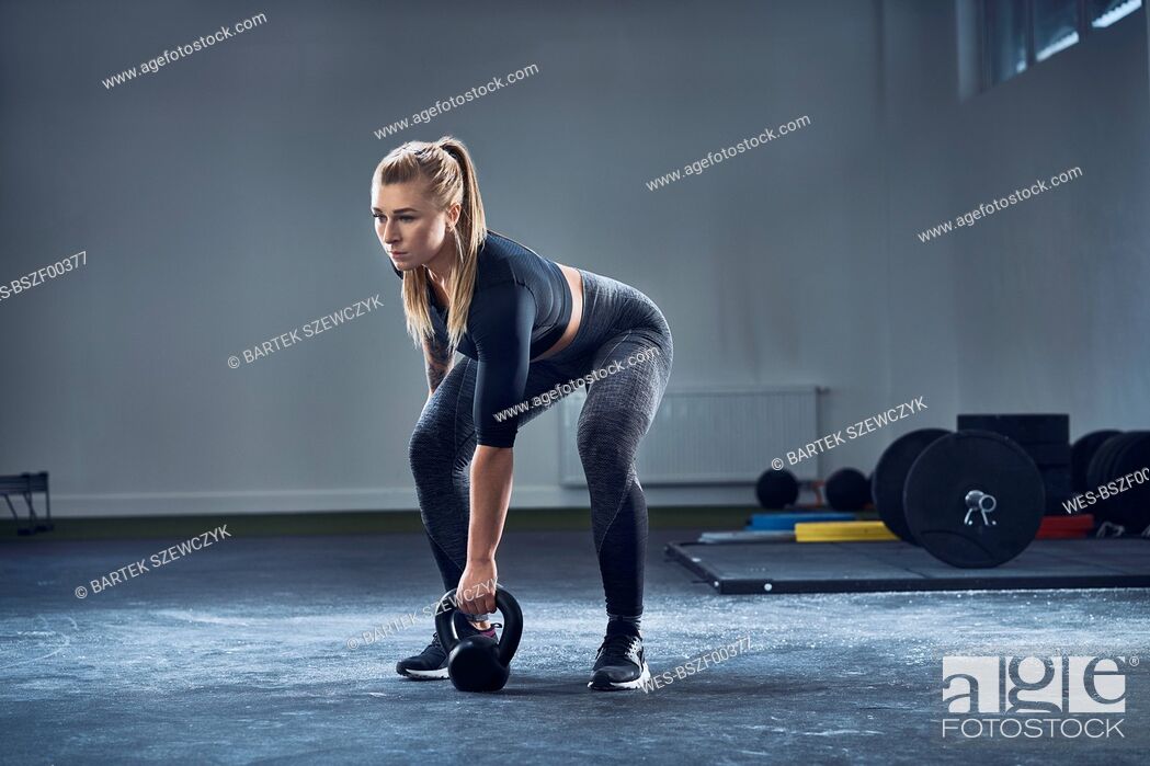 Imagen: Woman exercising with kettlebell at gym.