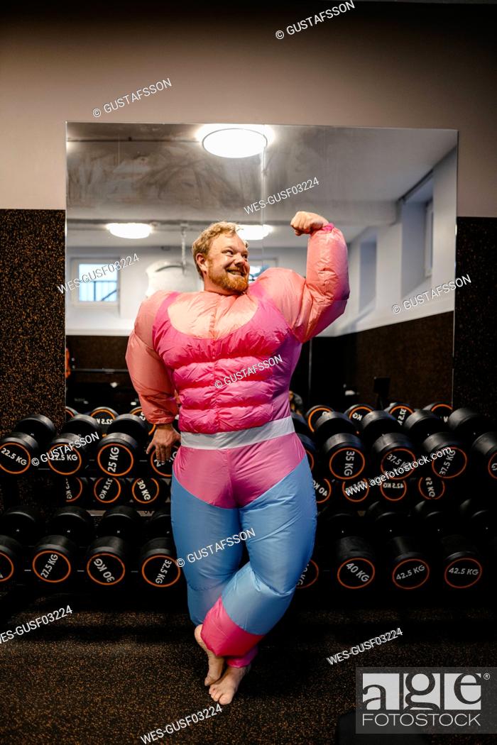 Stock Photo: Proud man wearing pink bodybuilder costume flexing his muscles.