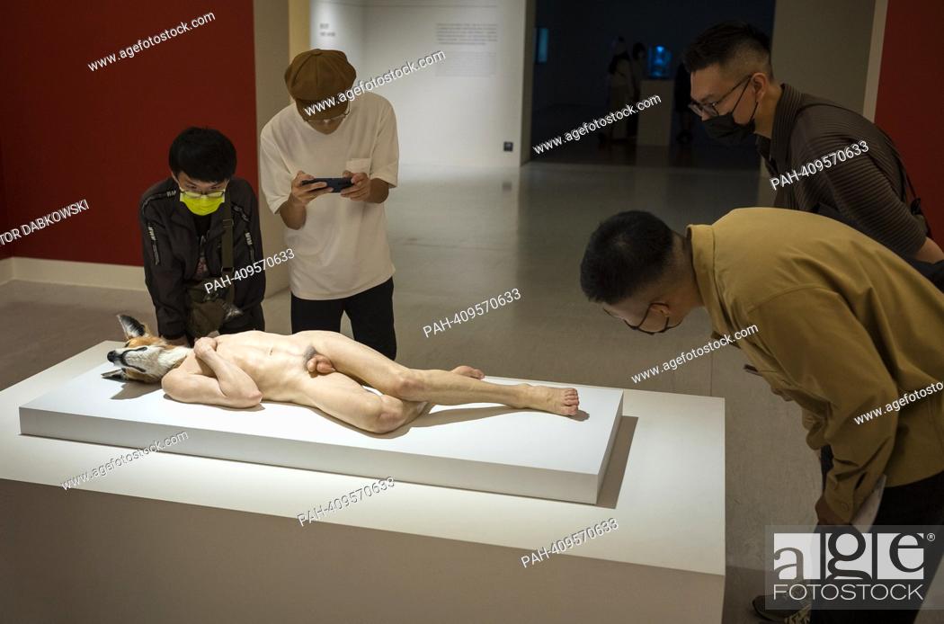 Stock Photo: People look at The Doghead a sculpture of naked man with dog head by Sam Jinks during the SUPERNATURAL: Sculptural Visions of the Body exhibition in Taipei.