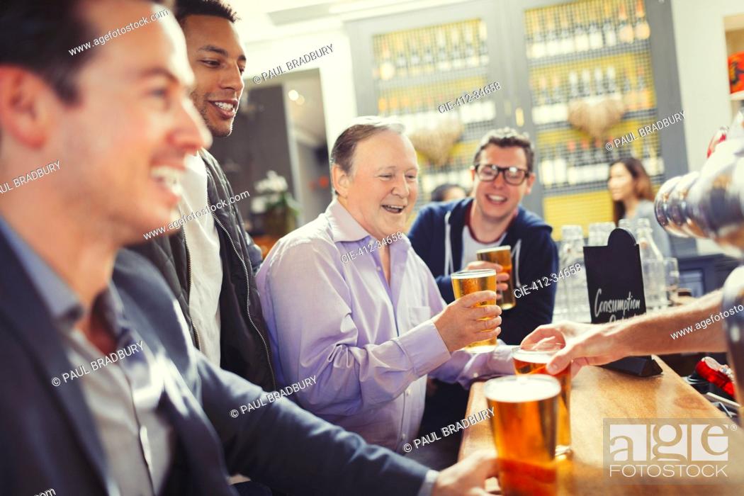 Stock Photo: Smiling men friends drinking beer at bar.