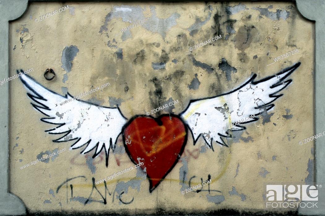 Stock Photo: Graffito zeigt ein stilisiertes rotes Herz mit zwei weissen Fluegeln. Querformat. Graffito shows a stylized red heart with two white wings.